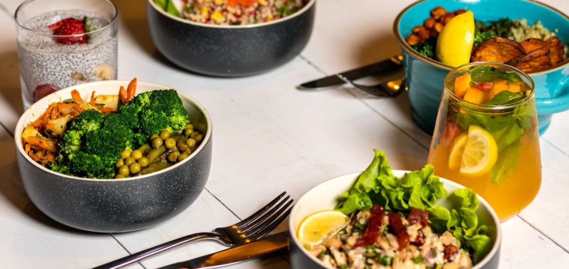 A vibrant assortment of healthy bowls and drinks showcasing fresh ingredients like broccoli and citrus.